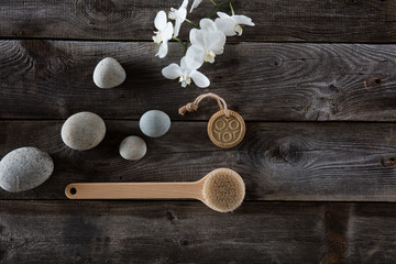 bodycare concept with pebbles, wooden back brush and white orchids, flat lay