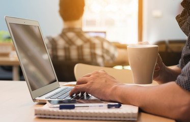 Man drinking coffee while using laptop in co-working space, noma