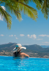 Woman relaxing in infinity pool looking at view