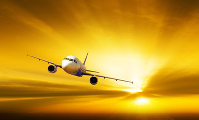 Fototapeta na wymiar Airplane with background of sunburst sky at sunset or sunrise, e