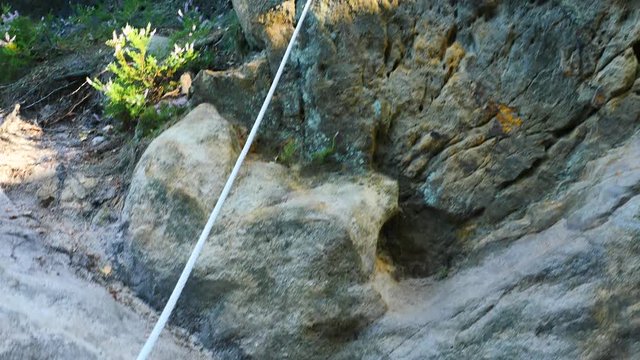 Climbers ladder. Iron twisted rope fixed in block by screws snap hooks. The rope end anchored into sandstone rock. 
