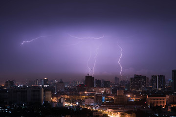Naklejka na ściany i meble Lightning storm over city in purple light