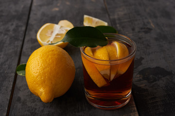 lemons with leaves and tea with lemon in a glass on the table