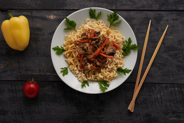 noodles on a plate, tomato, pepper and Chinese chopsticks