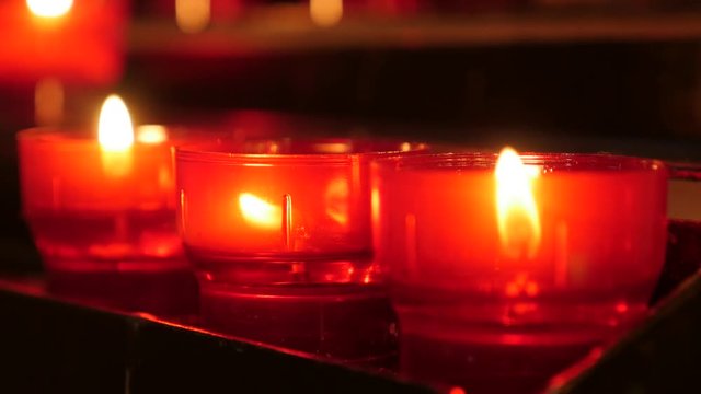 Lit of red of Christian catholic prayer votive candles in candle rack 4K 2160p 30fps UltraHD footage - Lot of red votive candles arranged in church 4K 3840X2160 UHD video 