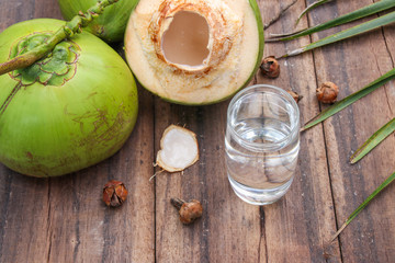 Fresh Coconut Water Drink in glass with coconut leaf on wooden  background