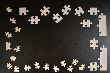 Puzzles on black background. Frame made of puzzle