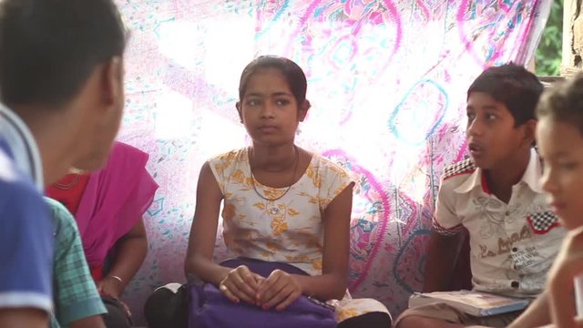 Student-teacher helps boys and girls in their studies, in a village school in Bengal, India still shot, narrow depth of field.