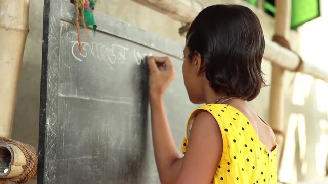 oung girl student in Bengal, India, writes in Bengali on a chalkboard