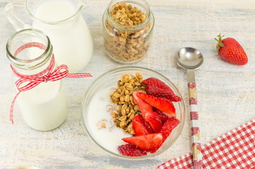 Granola cereals, fresh strawberries and bottle of milk
