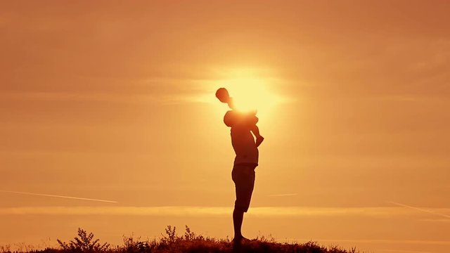 Dad keeps on his hands and throws baby son at sunset in the summer
