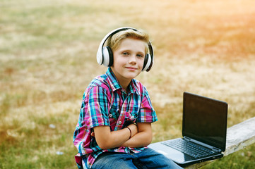 Boy listening to music in the city with a laptop