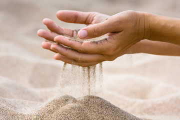 sand running through fingers of woman