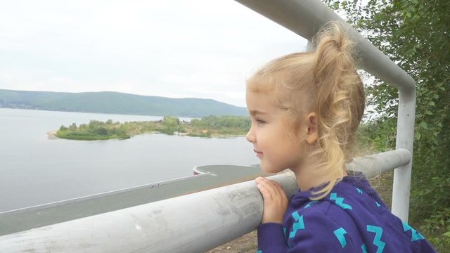 Girl looking forward to the horizon, watching the landscape of the river and mountains.