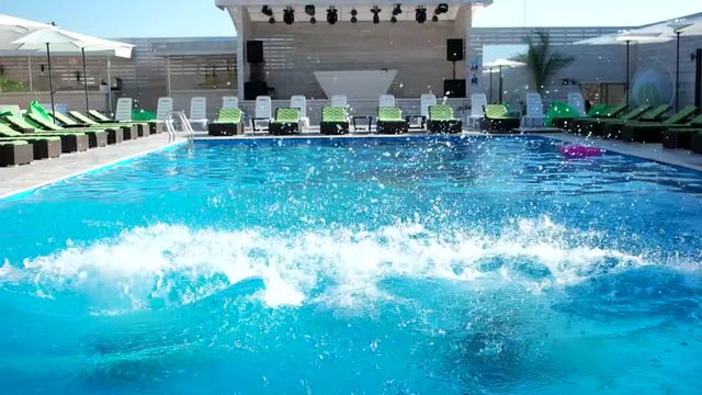 sexy girls dive into the pool, happy summer. funny girls jumping in the blue pool water, sunny day in the summer resort. attractive girl with beautiful figures in bathing suits bathing, swim.
