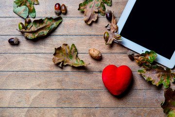 tablet, heart -shaped toy and fallen leaves