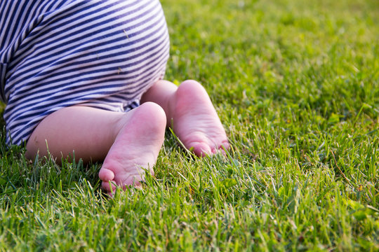 Close up. Happy Child Feet Barefoot on Green Grass. Healthy Lifestyle. Spring Time. Rear view. the concept of flatfoot, the child is learning to crawl