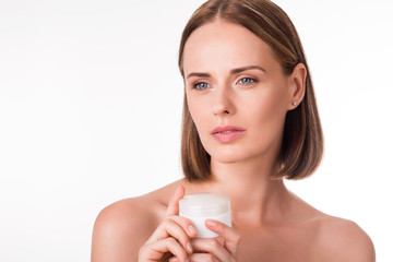 Cute young woman holding cream