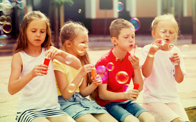 children blowing bubbles outdoors.