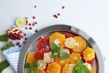 Plate with different citrus slices on light background