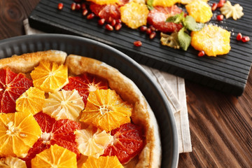 Delicious citrus cake in pan on wooden background