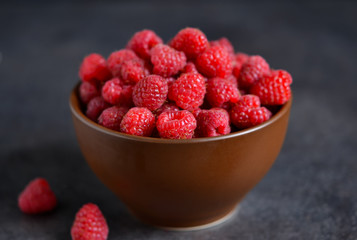 Fresh, juicy raspberries in a bowl on a black background