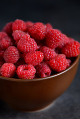 Fresh, juicy raspberries in a bowl on a black background