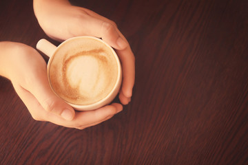 Female hands holding cup of coffee in cafe