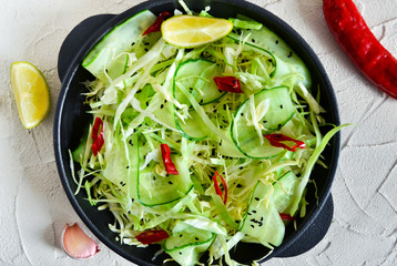 Salad with cucumber, cabbage, chilli and lime juice on a black b