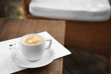 Cup of fresh coffee and morning newspaper on wooden table