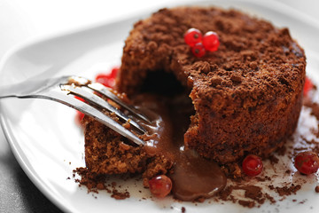 Tasty chocolate fondant with red currant on white plate, closeup
