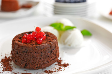 Tasty chocolate fondant with red currant on white plate, closeup
