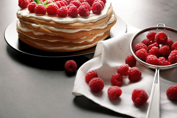 Raspberries in sieve and tasty cake on plate