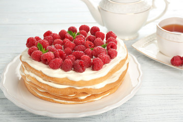 Tasty raspberry cake with fresh tea on wooden background