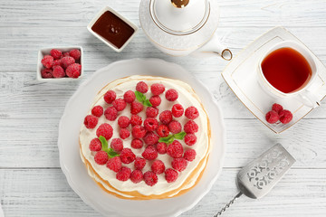 Tasty raspberry cake with fresh tea on wooden background