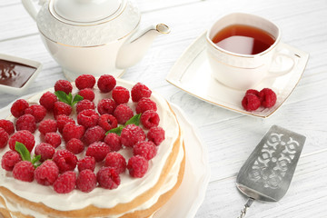 Tasty raspberry cake with fresh tea on wooden background
