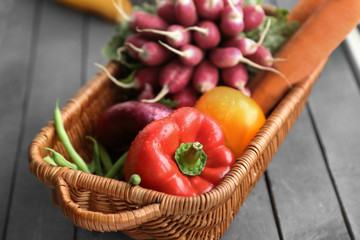 Fresh vegetables in wicker basket on table, closeup