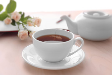 Cup of tea with flowers and notebook on table