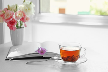Cup of tea with notebook and spoon on table