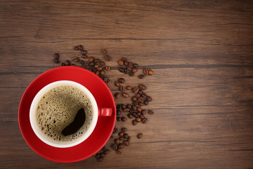 Cup of coffee with beans on wooden background