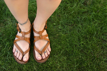 Female legs with tattoos on green grass