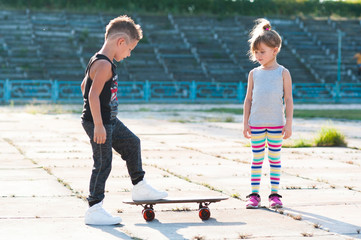 boy teaches girl to ride a skateboard