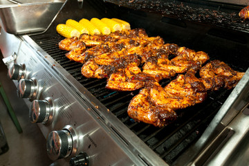 tasty chicken wings and corncobs on a modern gas grill machine