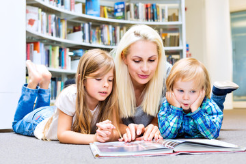Mother with little girl and boy read book together