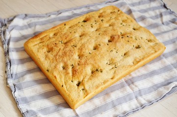 A freshly baked focaccia bread on a tea towel