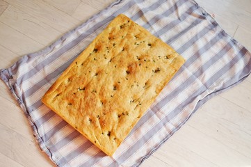 A freshly baked focaccia bread on a tea towel