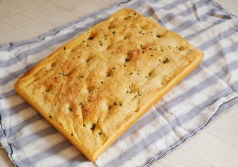 A freshly baked focaccia bread on a tea towel