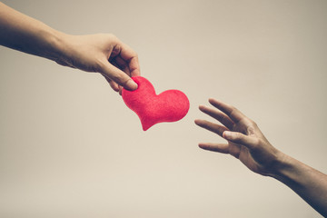 female hand giving a red heart to a male hand