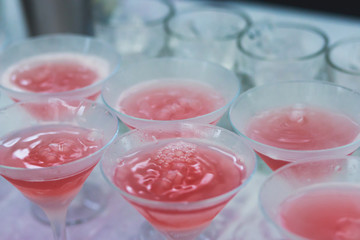 Beautiful row line of different colored alcohol cocktails on a party, martini, vodka,and others on decorated catering bouquet table on open air event, picture with beautiful bokeh
