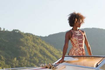 Summer vacation - young afro woman driving a motor boat on sunse